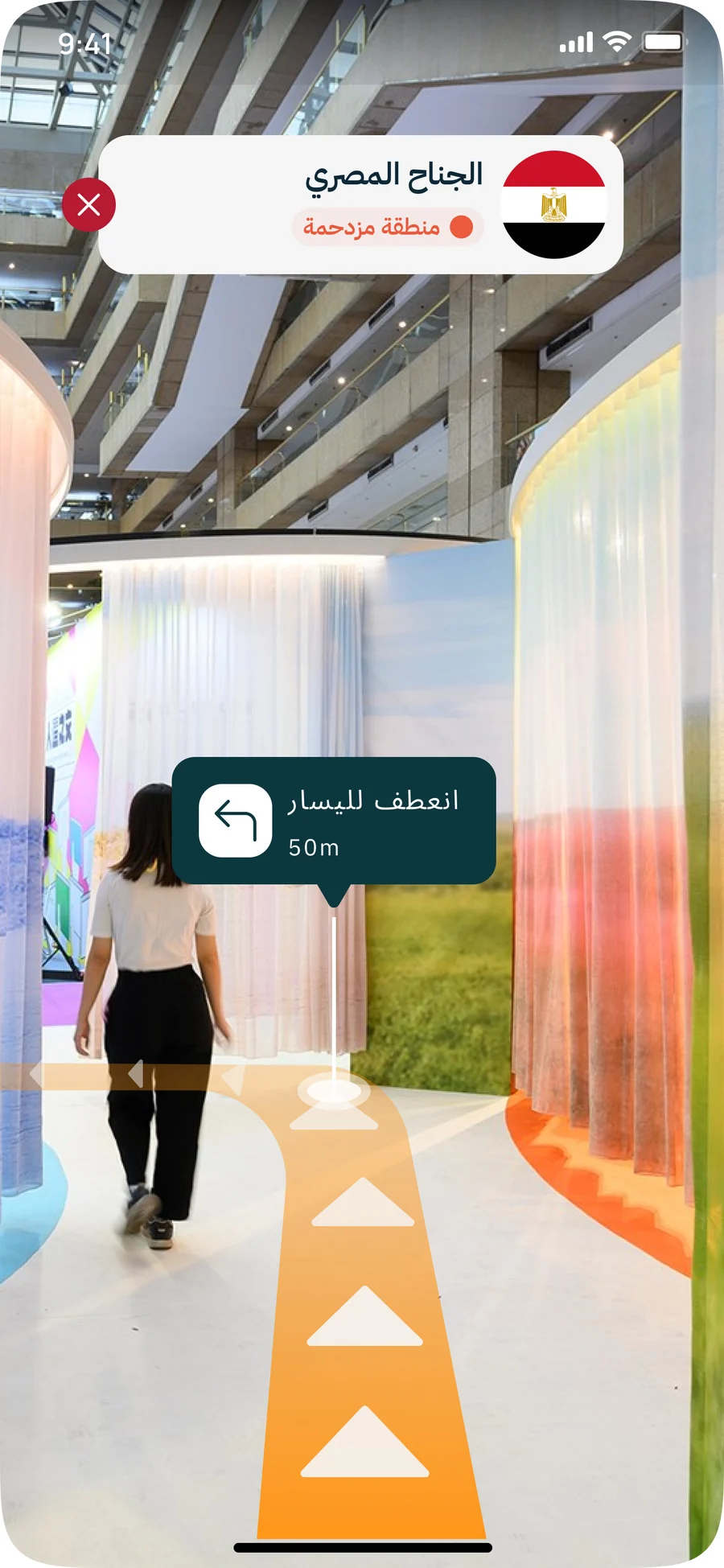 App screen: a camera view of the fair hall with an arrow path on the floor, a "turn left, 50 m" instruction, and a label for the Egyptian pavilion marked as a crowded area (phase 3 concept)